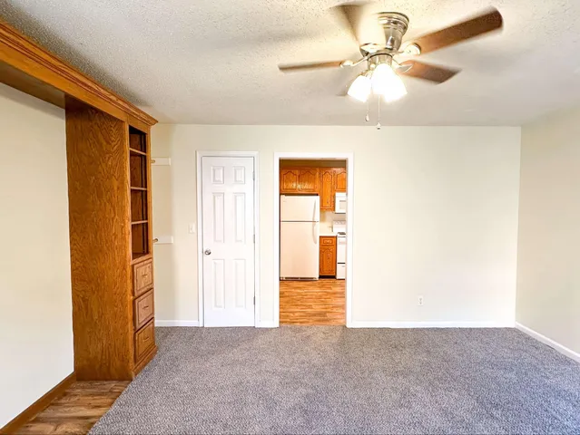 a kitchen with stainless steel appliances granite countertop a refrigerator a sink a stove and white cabinets with wooden floor