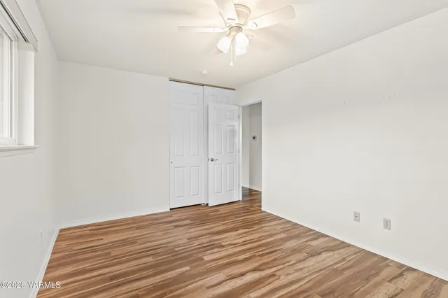 a view of a room with wooden floor and ceiling fan