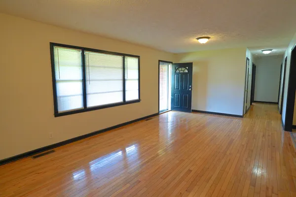 a view of an empty room with wooden floor and a window