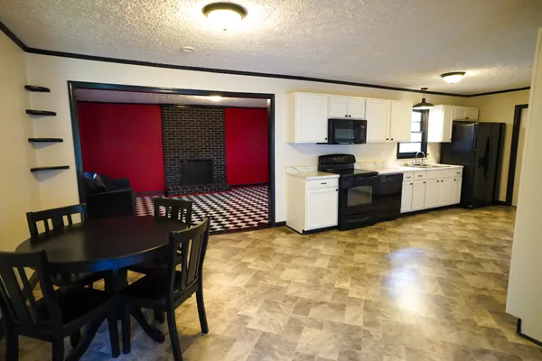 a kitchen with stainless steel appliances granite countertop a stove top oven a sink a dining table and chairs