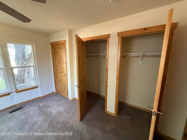 a view of an empty room with window and closet area