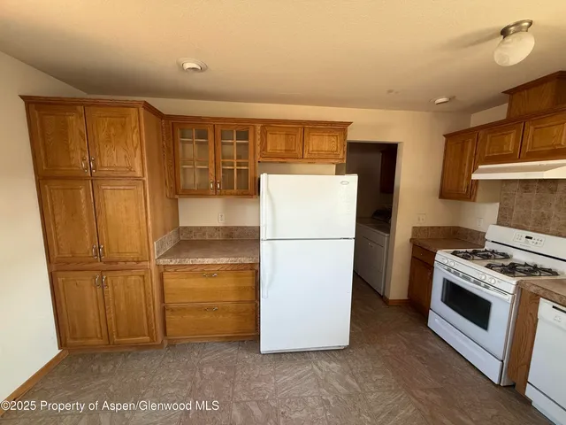 a kitchen with a refrigerator a stove top oven and cabinets