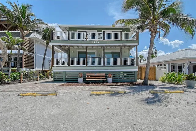 front view of a house with a yard and palm trees