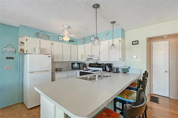 a kitchen with a refrigerator a sink dishwasher a stove a dining table and chairs