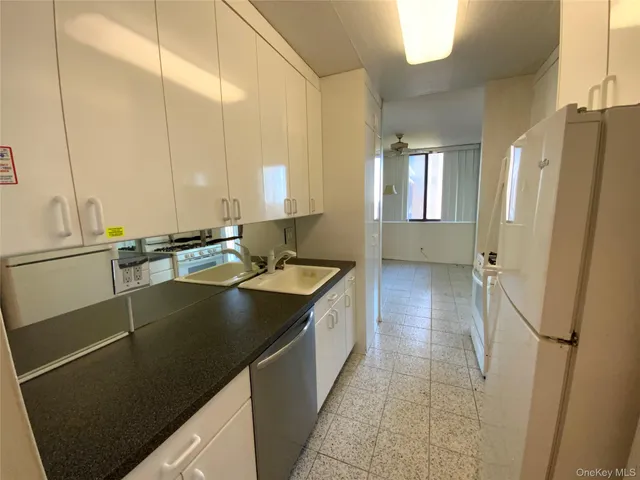 a kitchen with stainless steel appliances granite countertop a refrigerator a sink and white cabinets