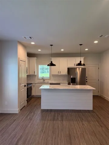 a living room with stainless steel appliances kitchen island hardwood floor sink stove and wooden floor