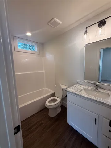 a bathroom with a granite countertop sink toilet a large mirror a bathtub and shower