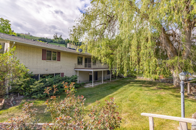 1365 Sumac Drive Logan, UT 84321 - Photo 59 of 66 Rear exterior featuring a brick facade, upper-level balcony, and lower-level patio with stone pavers