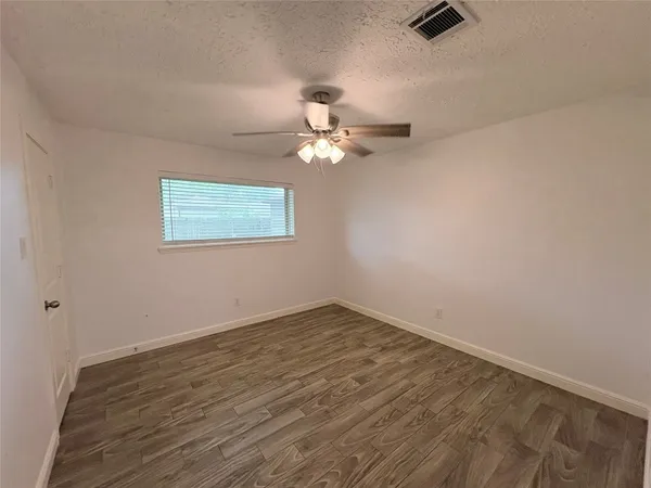 an empty room with a window and a ceiling fan