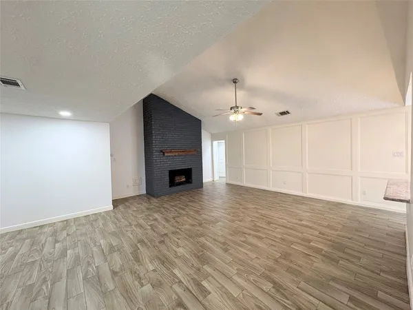 a view of empty room with wooden floor and fireplace
