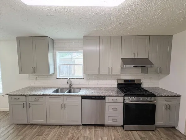 a kitchen with granite countertop a sink stove and cabinets