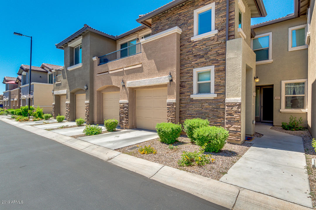 7726 East Baseline Road, Unit 143 Mesa, AZ 85209 - Photo 2 of 27 a front view of a house with a yard and a garage