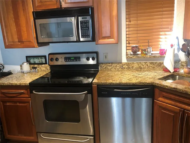 a kitchen with granite countertop a refrigerator and a stove top oven
