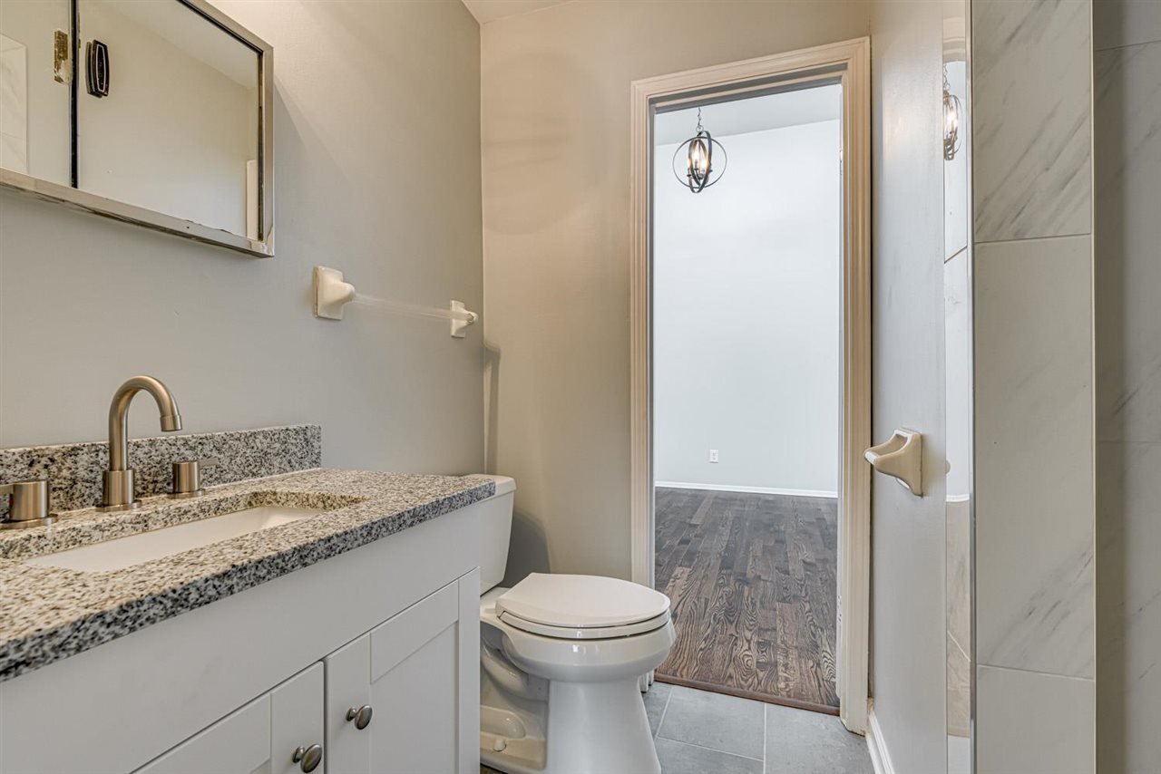 5565 Pleasant View Road, Unit 5565 Memphis, TN 38134 - Photo 15 of 25 a bathroom with a granite countertop toilet a sink and a mirror
