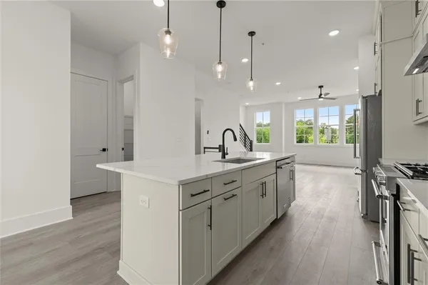 a large white kitchen with a large island oven a sink and stainless steel appliances