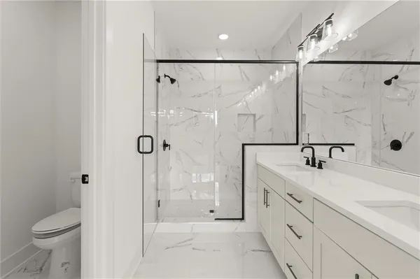 a bathroom with a shower sink vanity mirror and toilet