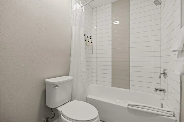 a white toilet and tub sitting next to a bathroom sink