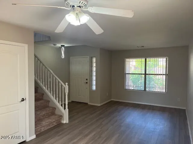 an empty room with wooden floor fan and windows