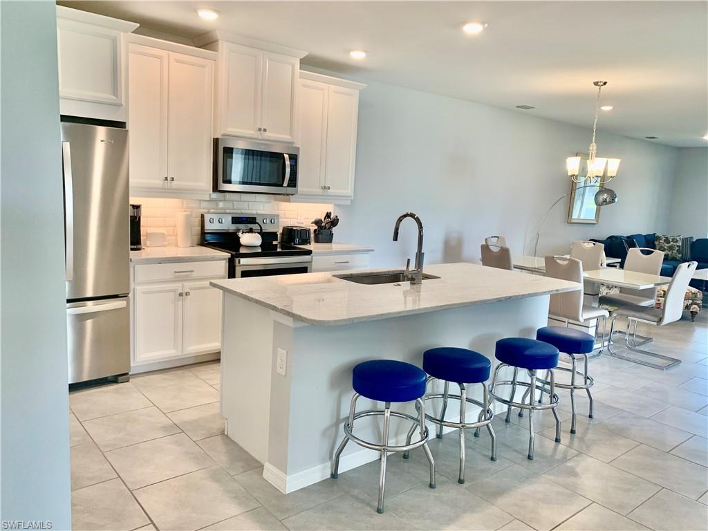 14632 Edgewater Circle Naples, FL 34114 - Photo 13 of 35 a kitchen with stainless steel appliances a refrigerator stove a sink a dining table and chairs