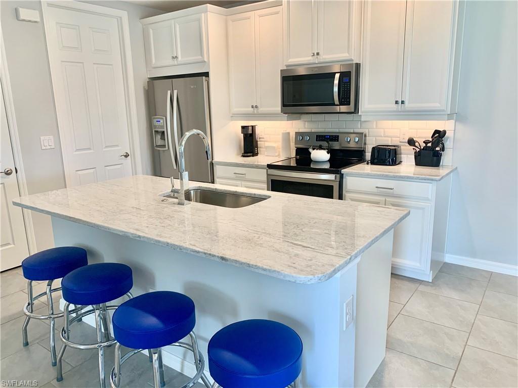 14632 Edgewater Circle Naples, FL 34114 - Photo 14 of 35 a kitchen with stainless steel appliances granite countertop a sink a stove and a refrigerator