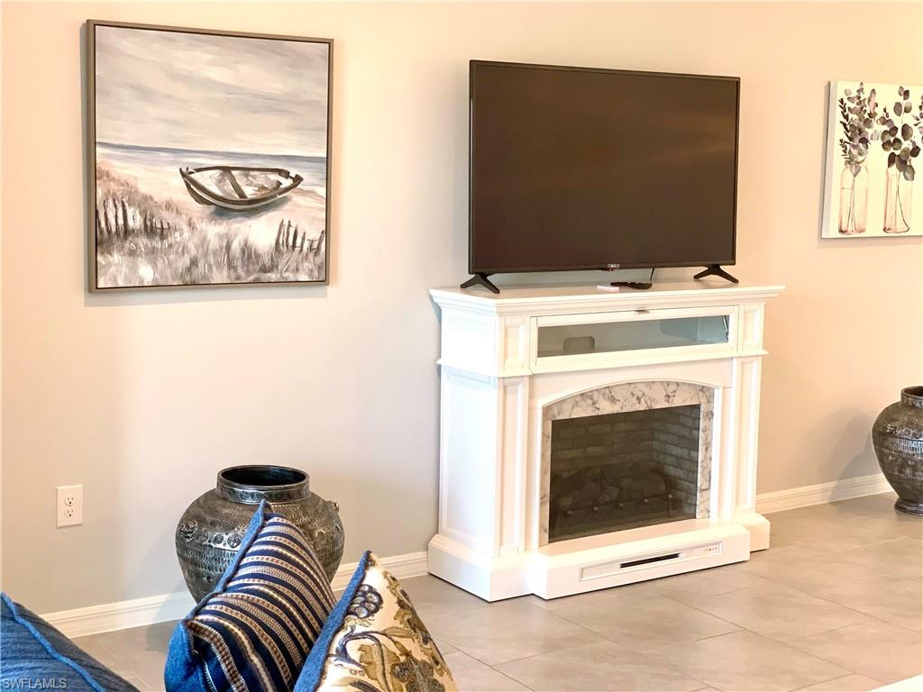 14632 Edgewater Circle Naples, FL 34114 - Photo 7 of 35 a living room with a fireplace and a flat screen tv