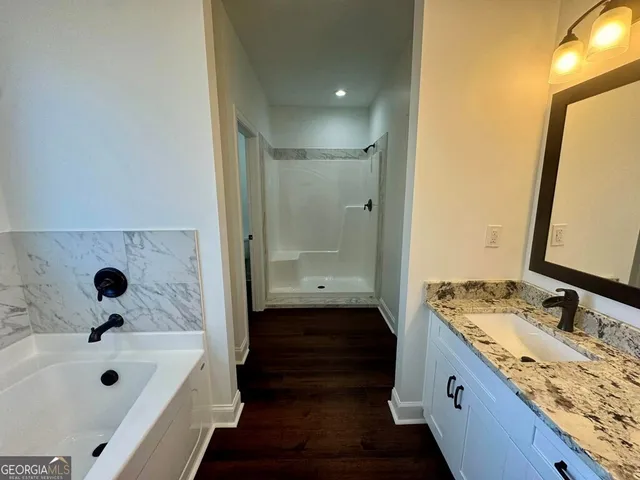 a bathroom with a granite countertop sink a mirror and a bathtub