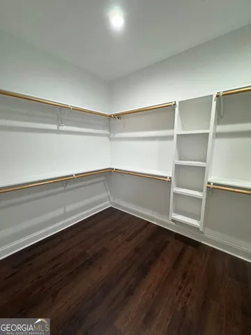 a view of an empty room with wooden floor and closet