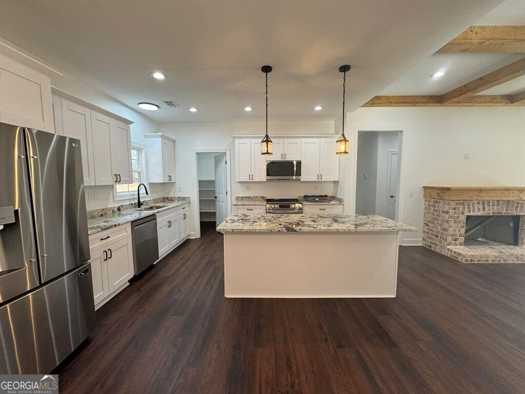 230 Woodland Heights Road Dublin, GA 31021 - Photo 5 of 30 a kitchen with kitchen island a sink a stove a refrigerator and white cabinets