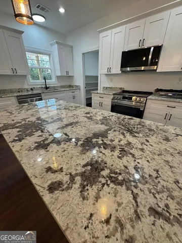 a kitchen with kitchen island a stove a sink and a microwave