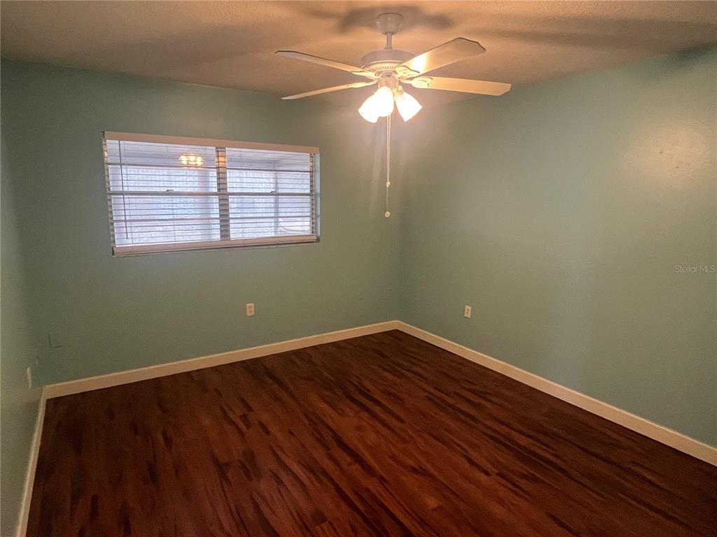 11718 Bayonet Lane, Unit A New Port Richey, FL 34654 - Photo 13 of 41 an empty room with wooden floor fan and windows