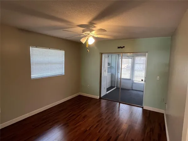 a view of an empty room with wooden floor and a window