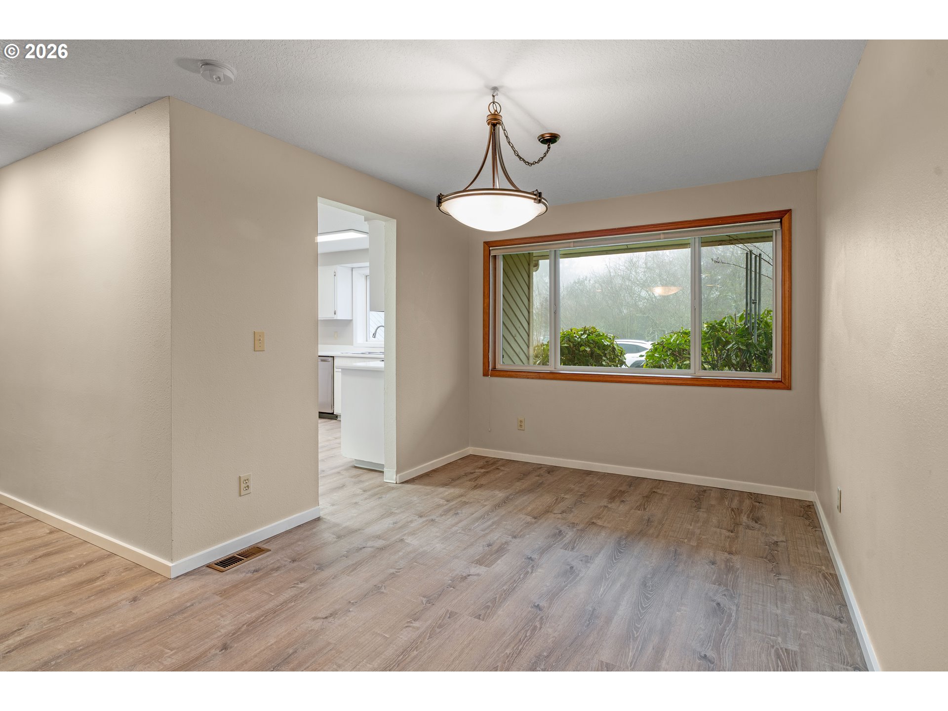 17839 Southwest Meadowbrook Way Beaverton, OR 97078 - Photo 10 of 45 a view of an empty room with wooden floor fridge and a window