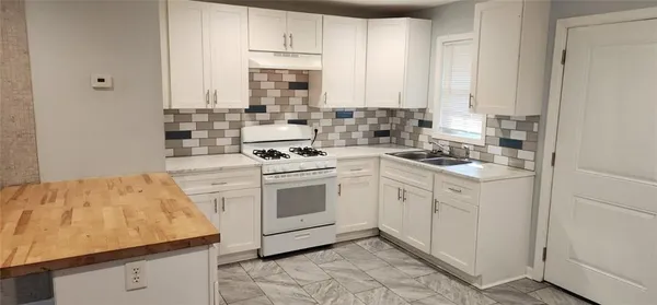 a kitchen with granite countertop white cabinets and white appliances