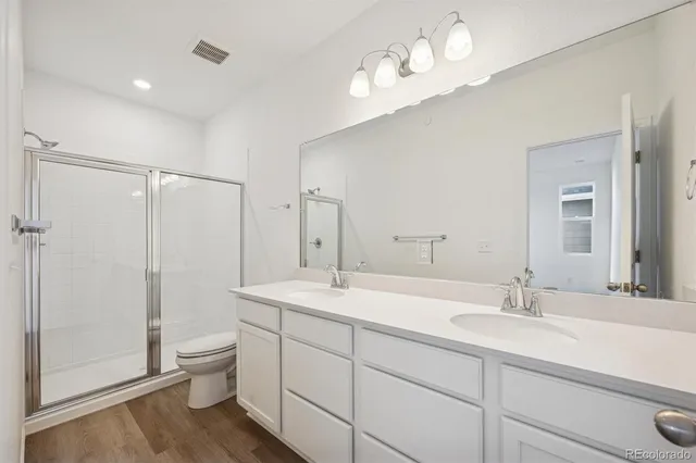 a bathroom with a double vanity sink toilet mirror and shower