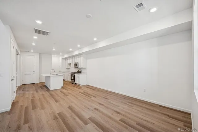 a view of a kitchen with kitchen island a sink wooden floor and a refrigerator