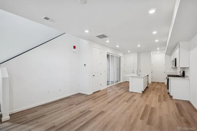 a view of kitchen with stainless steel appliances refrigerator oven and white cabinets with wooden floor