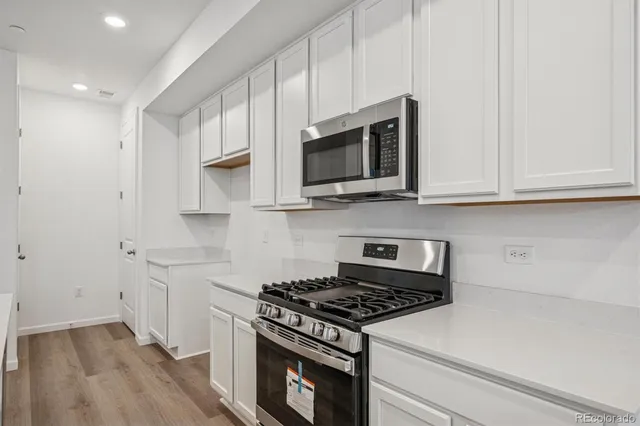 a kitchen with stainless steel appliances granite countertop white cabinets and a stove top oven