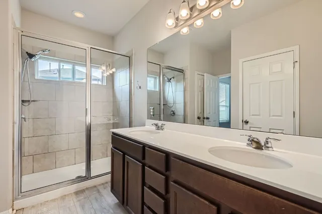 a bathroom with a double vanity sink mirror and shower