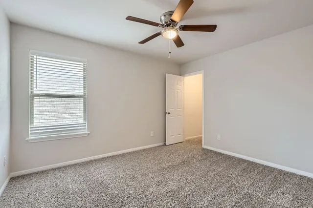 an empty room with a window and a fan