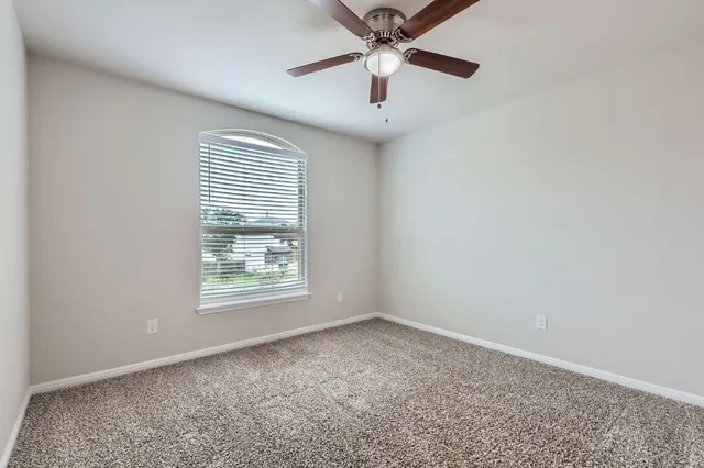 an empty room with a window and a fan
