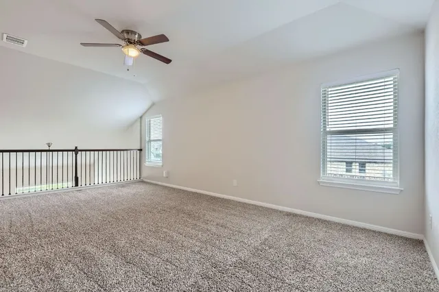 an empty room with windows and fan