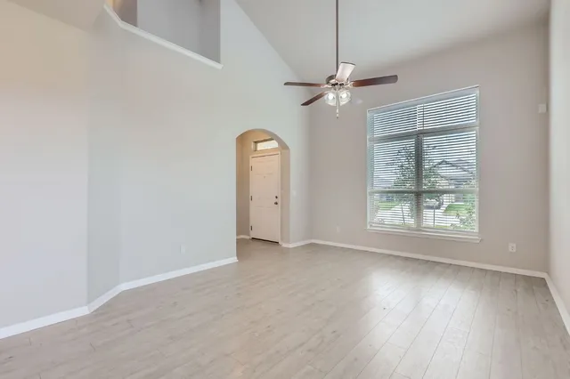 a view of a livingroom with wooden floor a ceiling fan and windows