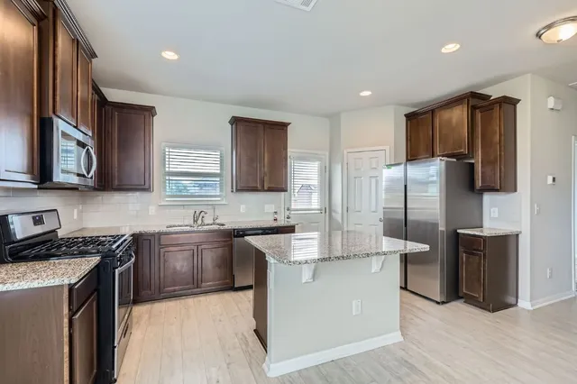 a kitchen with stainless steel appliances granite countertop a sink stove refrigerator and cabinets