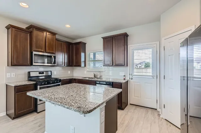 a kitchen with stainless steel appliances granite countertop a sink stove microwave and refrigerator