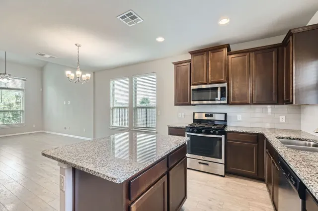 a kitchen with stainless steel appliances granite countertop a sink stove microwave and refrigerator