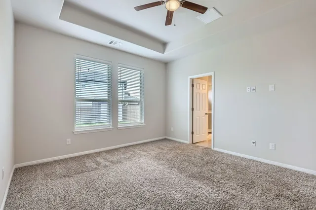 an empty room with ceiling fan and windows