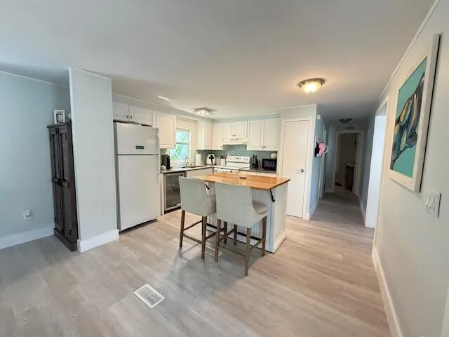 a kitchen with stainless steel appliances a refrigerator a stove a sink dishwasher and a dining table with wooden floor
