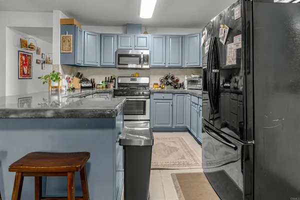 a kitchen with stainless steel appliances granite countertop a stove top oven a sink dishwasher a dining table and chairs with wooden floor