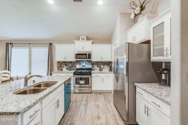 a kitchen with stainless steel appliances granite countertop a sink stove refrigerator and cabinets