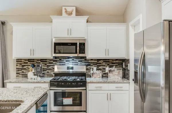 a kitchen with stainless steel appliances granite countertop a stove a refrigerator and a microwave